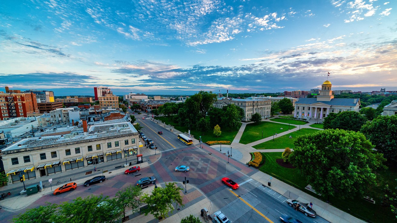 A panoramic view of the University of Iowa Pentacrest with the golden dome of Old Capitol beneath a cloud-filled sky